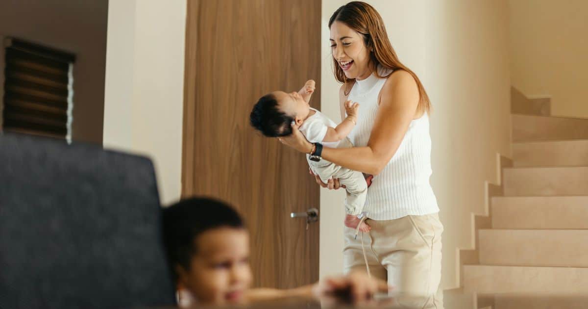 New mom with newborn and sibling during postpartum babymoon at home