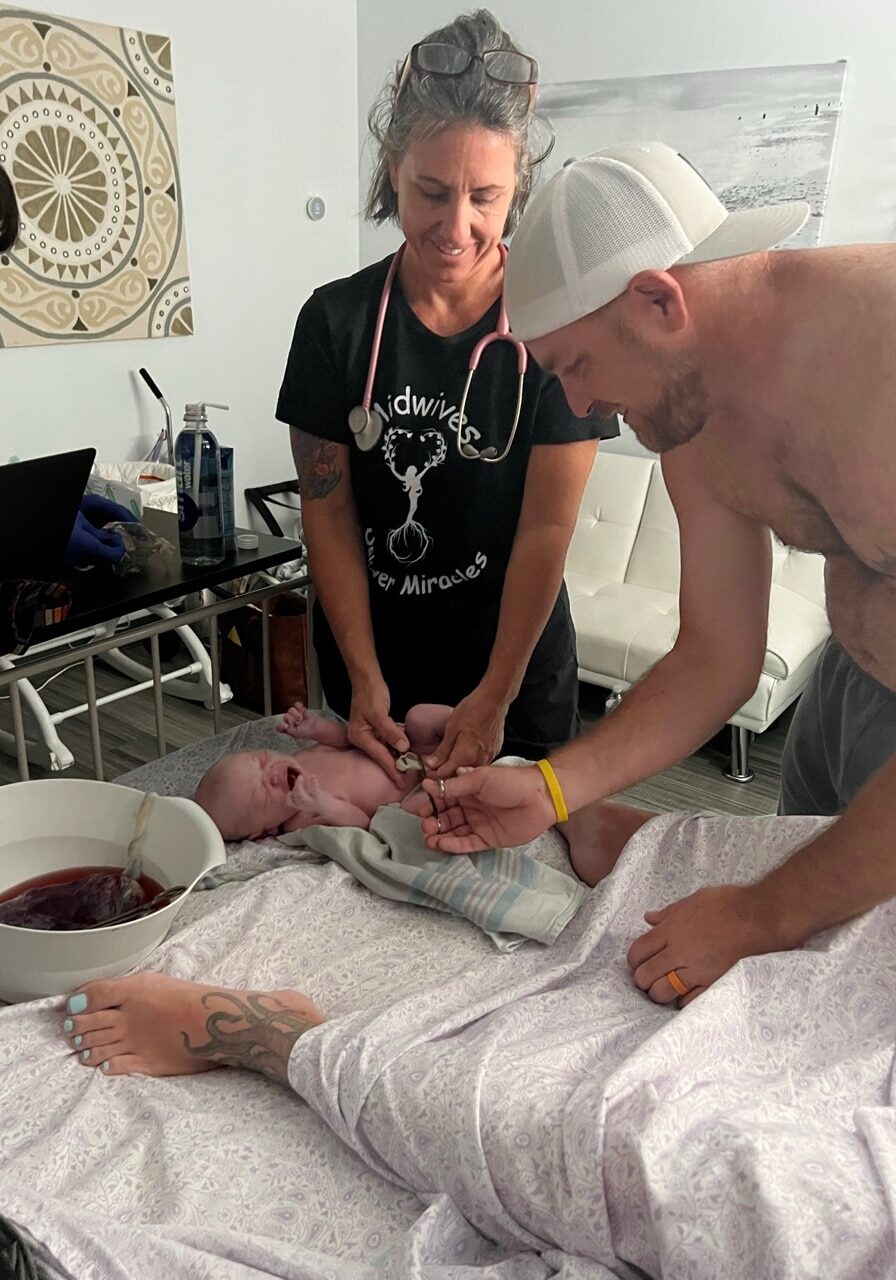 midwife newborn check at birth center with dad cutting the cord
