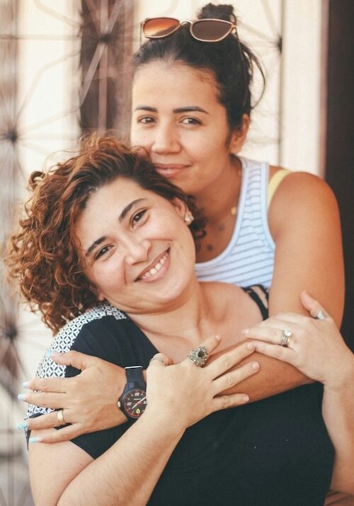 Two women hug and smile at camera